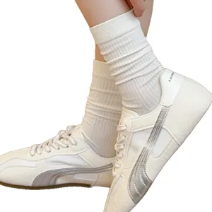 Chaussettes mi-hautes côtelées blanches associées à des baskets décontractées pour femmes d'été.