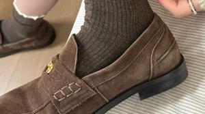 Brown suede loafers paired with cozy ribbed socks, lifestyle detail shot, retro footwear fashion.