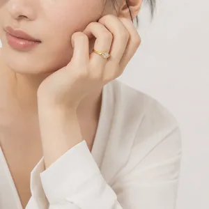Gros plan détaillé d'une élégante bague chevalière dorée en zircone marquise portée main.