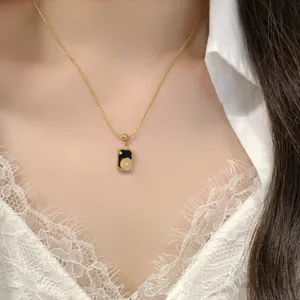 Détail de collier pendentif carte de tarot doré avec pierre naturelle et fine chaîne.