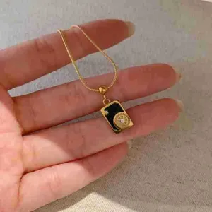 Gros plan d'un élégant collier avec pendentif carré carte de tarot et fine chaîne.