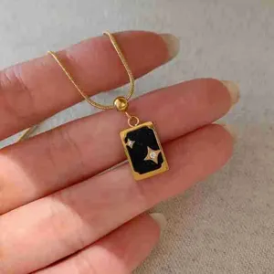 Collier pendentif carte de tarot en acier dore avec detail etoile brillante closeup