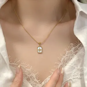 Gros plan sur le détail du collier pendentif en nacre carrée avec un joli charm étoile.