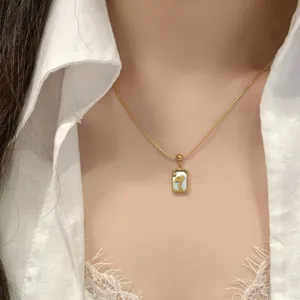 Gros plan détaillé du collier pendentif en pierre naturelle carrée avec une chaîne dorée.