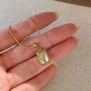 Collier pendentif tarot en acier titane élégant avec détail floral en nacre blanche.