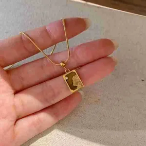 Gros plan du collier pendentif carte de tarot en acier titane avec pierre naturelle.