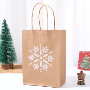 Detail shot of kraft paper Christmas gift bag with white snowflake print and handles.