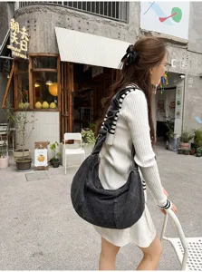 Detailed street scene view of casual dark denim hobo shoulder bag featuring stylish pleated strap.