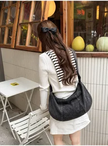 Casual denim shoulder bag detail showing slouchy pleated design, large capacity and durable strap.