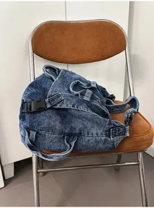 Detail view of a vintage washed denim crossbody bag placed on a retro folding chair.