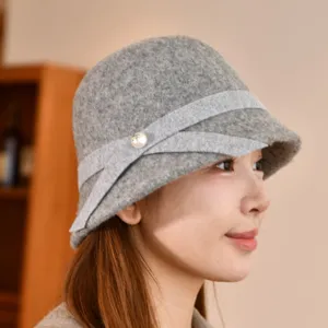 Close-up detail of the grey wool bucket hat featuring an elegant ribbon bow and pearl charm.