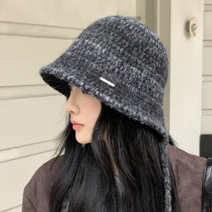 Detail shot of a knitted bucket hat in dark grey, featuring a wide brim and side strap.