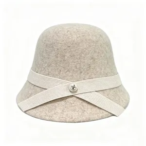 Detail view of beige wool cloche hat with cross ribbon and pearl button for autumn and winter.