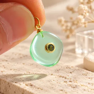 Detailopname van een prachtige groene edelsteenhanger met vergulde metalen hangerbeugel.