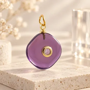 Gedetailleerd shot van een paarse geometrische edelsteenhanger met gouden oog en kristal.