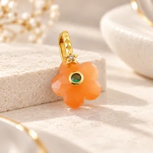 Exquisito colgante de flor de cinco pétalos con gema naranja vibrante y verde.