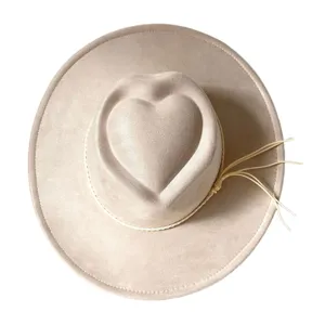 Detail view of a light beige faux suede western cowboy hat with a unique heart crown and fringe.