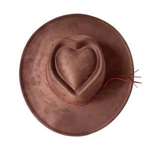 Close-up of brown suede western cowboy hat with heart crown and tassel detail, top view.