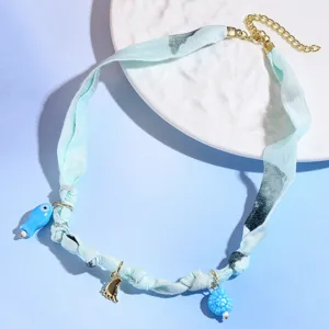 Detailed view of the resort style blue fabric choker necklace with cute fish and shell pendants.