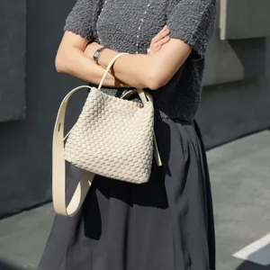 Vue détaillée du sac seau chic en cuir tissé avec bandoulière dans une teinte crème neutre.