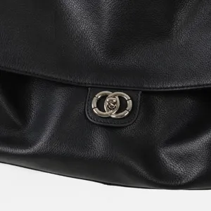Gros plan d'un sac à épaule de travail en cuir véritable noir avec fermoir métallique élégant.