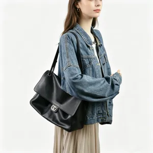 Sac à épaule classique en cuir noir avec fermoir métallique porté par un mannequin.