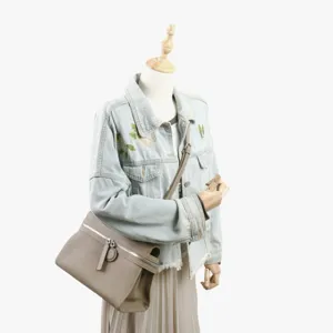 Vue détaillée d'un sac bandoulière en cuir véritable associé à une veste en jean brodée.