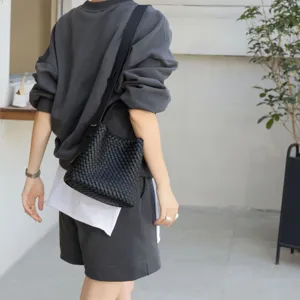 Vue detaillee du sac seau bandouliere en cuir tisse noir, texture elegante et tendance.