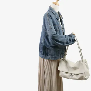 Veste en jean décontractée associée à un sac bandoulière en cuir souple blanc détail