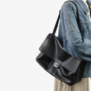 Vue détaillée d'un sac à bandoulière en cuir souple noir porté sur l'épaule du modèle.