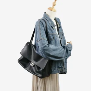 Sac à main bandoulière en cuir noir pour femme, grand cabas souple avec fermoir métal.