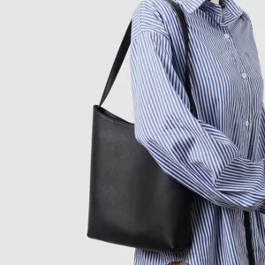 Vista dettagliata di una borsa a secchiello nera in vera pelle con camicia a righe.