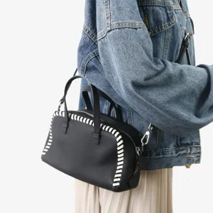 Sac a main Boston en cuir noir avec details de coutures blanches, elegante bandouliere.