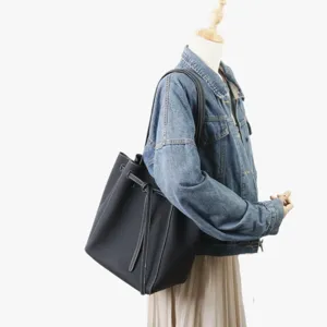 Vue détaillée du sac cabas seau en cuir noir avec coutures contrastées et nœud élégant.
