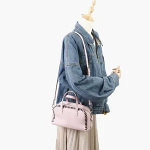 Vue détaillée du sac Boston en cuir rose avec laçage cousu main et finitions métalliques.