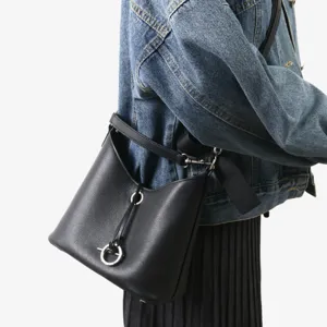 Vue détaillée du sac seau en cuir noir avec fermeture à anneau unique et bandoulière.