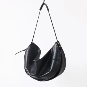 Détail de sac porté épaule demi-lune en cuir noir, sac aisselles style paresseux.