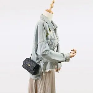 Chic sac bandoulière en cuir matelassé noir associé à une veste en jean brodée vintage.