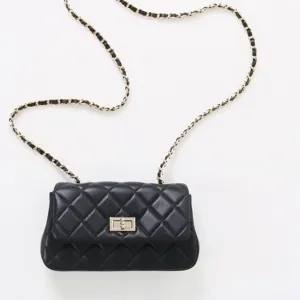 Détail de sac bandoulière en cuir matelassé noir, chaîne classique et fermoir tourniquet.