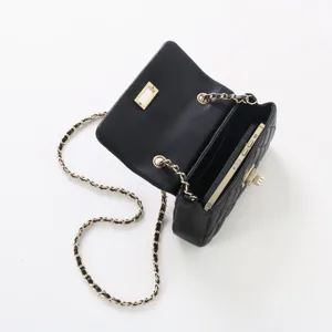 Détail de sac à bandoulière en cuir matelassé noir avec chaîne dorée et fermoir chic.