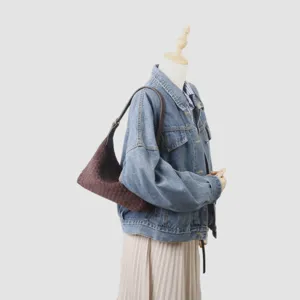Sac hobo sous les bras en cuir tressé artisanal, vue détaillée montrant texture et savoir-faire.