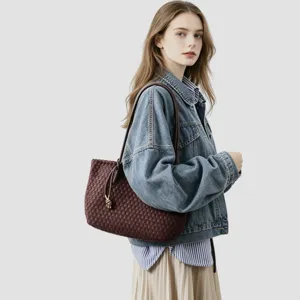 Vue détaillée d'un sac cabas d'épaule en cuir tressé marron foncé porté par un mannequin.