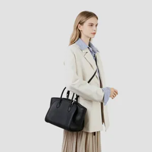 Vue rapprochée du sac cabas en cuir noir porté par le mannequin élégamment habillé.