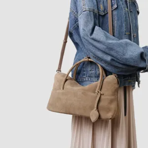Vue détaillée du sac à main en daim kaki avec texture douce, double poignée et bandoulière.