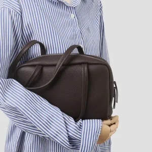 Vue détaillée du sac de bowling en cuir marron foncé, texture de cuir souple et poignées.