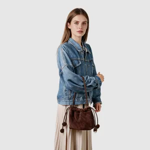 Vue detaillee du sac seau marron en sude matelasse avec cordon porte par le modele.