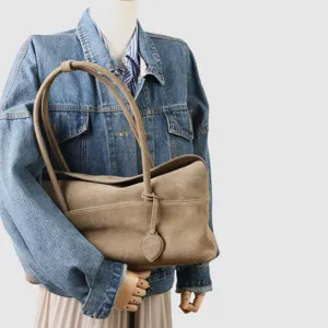 Vue détaillée du sac en suédine avec texture douce, poignées et coutures soignées.