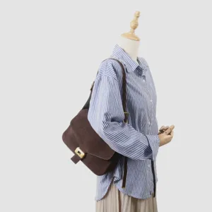 Vue détaillée du sac à bandoulière en daim marron avec fermoir métallique sur mannequin.