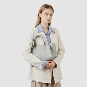 Sac cabas minimaliste en cuir gris tenu par un mannequin, grand sac à main élégant.
