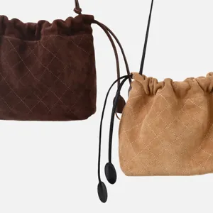 Vue détaillée des sacs-poches matelassés en suédine à cordon en marron et chameau, texture.